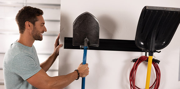 Man placing a shovel onto a wall